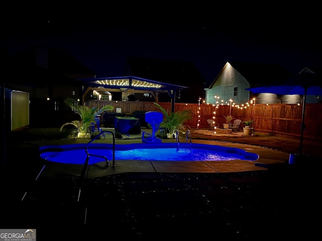 pool at night featuring a gazebo, fence, and a patio area