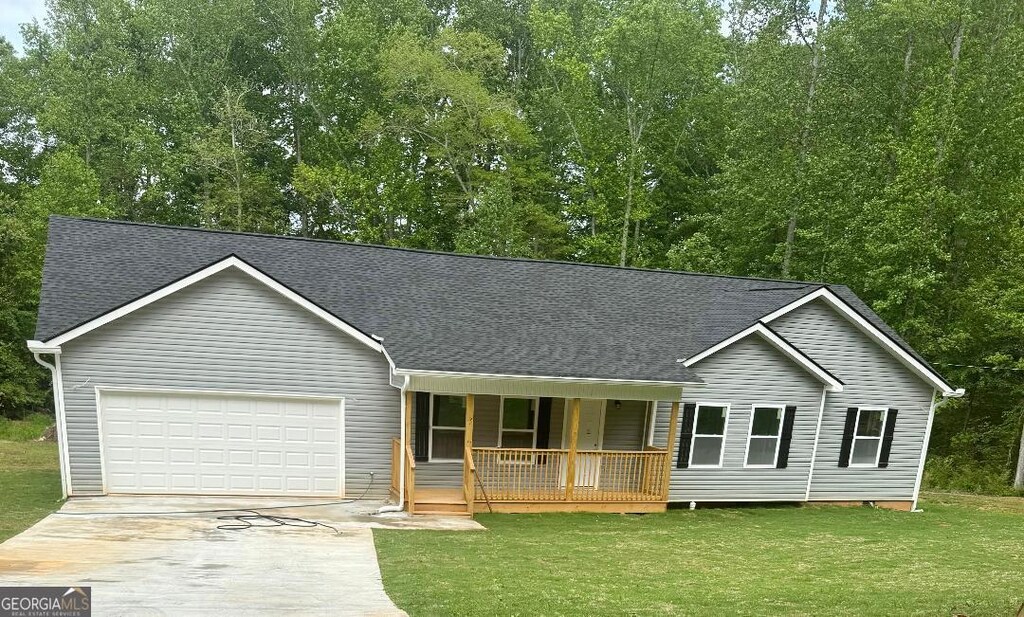 view of front of property featuring a porch, driveway, an attached garage, and a shingled roof