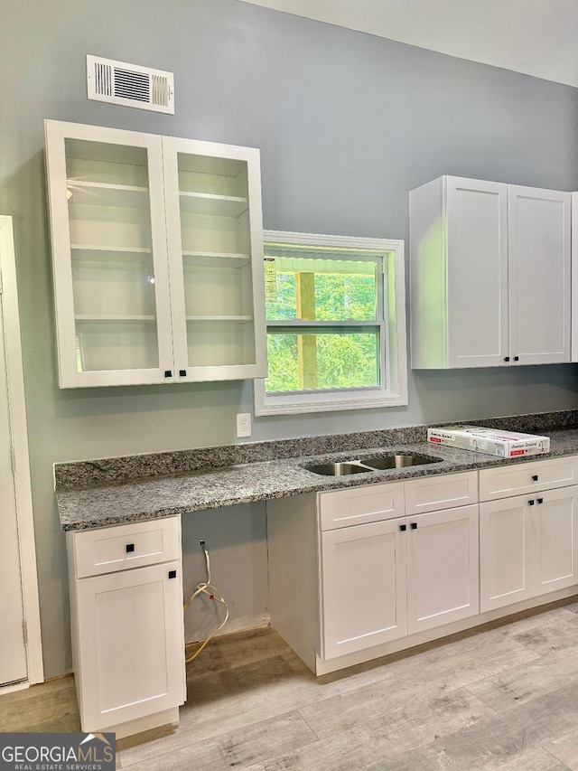 191 Deerfield Ln, Carrollton, GA 30116 - kitchen featuring light wood-style flooring, dark stone countertops, and white cabinets
