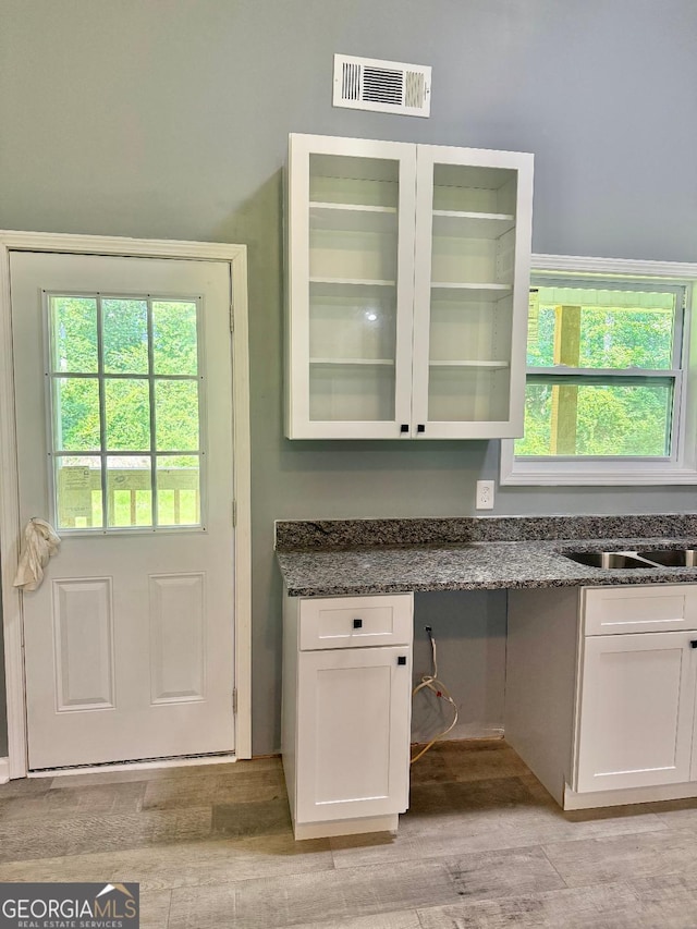 191 Deerfield Ln, Carrollton, GA 30116 - interior space with white cabinetry, glass insert cabinets, light wood finished floors, and dark stone counters
