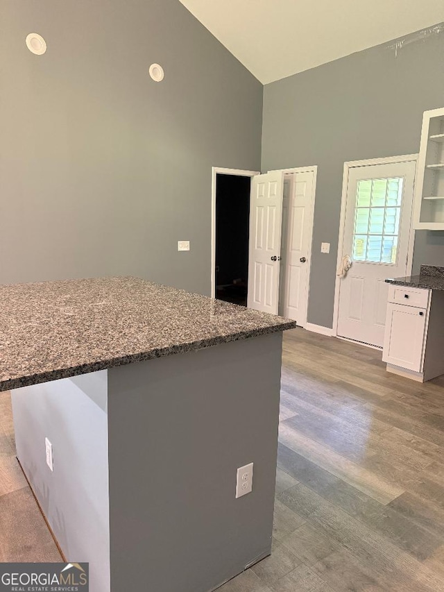 191 Deerfield Ln, Carrollton, GA 30116 - kitchen with dark stone countertops, white cabinets, high vaulted ceiling, and wood finished floors