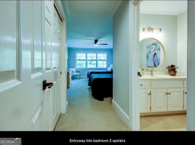 hallway featuring light carpet, a sink, and baseboards