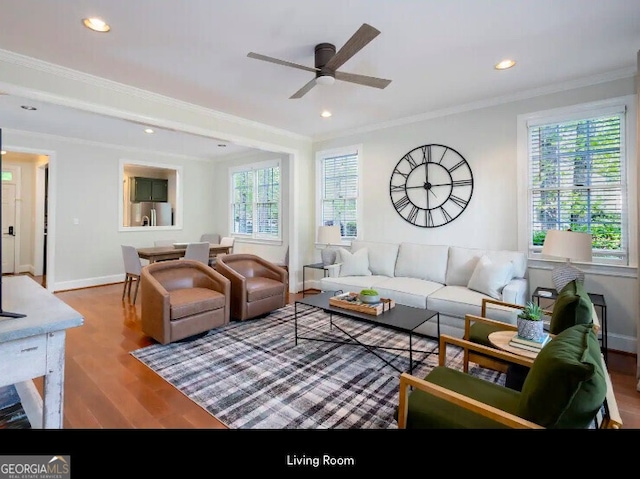 living area with crown molding, wood finished floors, a ceiling fan, recessed lighting, and baseboards