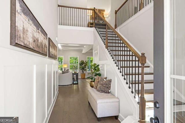 staircase with wood finished floors and a high ceiling