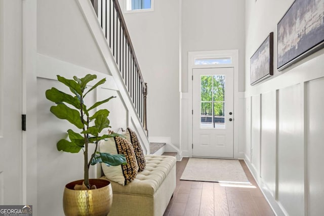 doorway with stairway, a towering ceiling, and wood finished floors