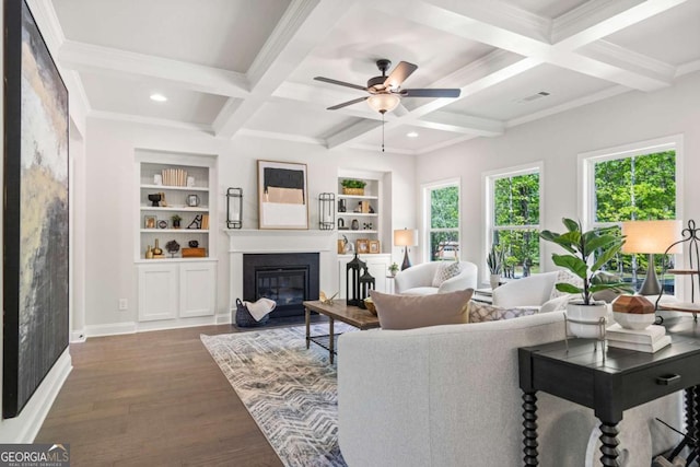 living room featuring coffered ceiling, a fireplace with flush hearth, a ceiling fan, wood finished floors, and beamed ceiling