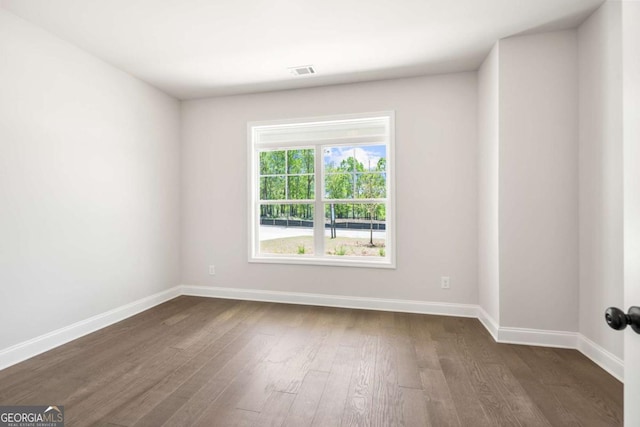 unfurnished room with dark wood-type flooring and baseboards