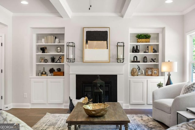 living area with dark wood-style floors, crown molding, a glass covered fireplace, recessed lighting, and beam ceiling