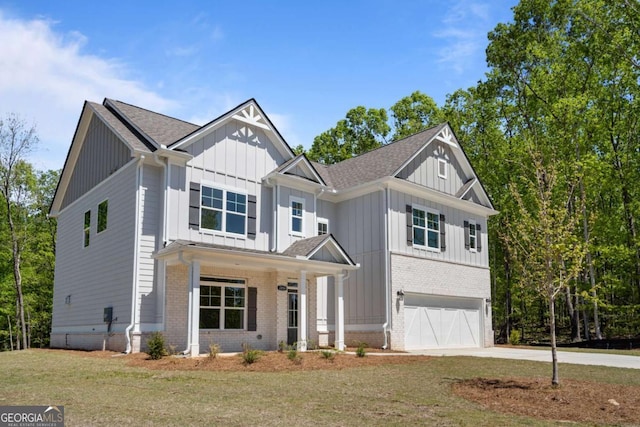 view of front of property featuring board and batten siding, an attached garage, brick siding, driveway, and a front yard