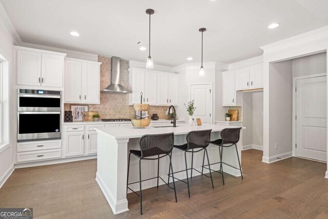 2749 Porches Ln, Dacula, GA 30019 - kitchen featuring wall chimney exhaust hood, stainless steel double oven, white cabinetry, gas stovetop, and ornamental molding