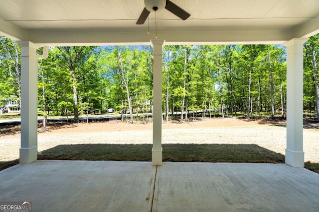 view of patio / terrace featuring a ceiling fan and view of wooded area