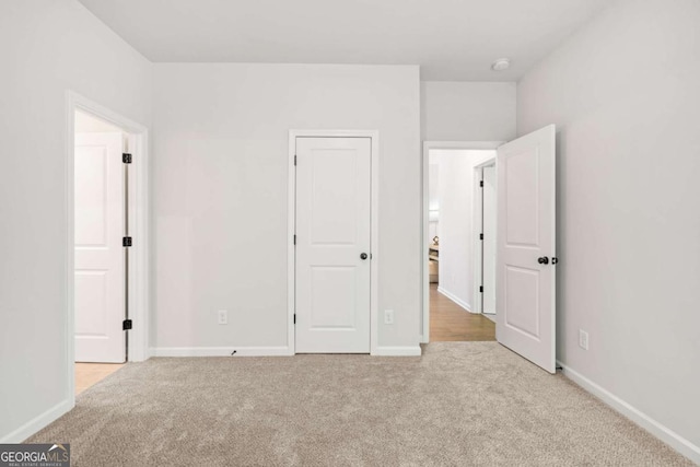 unfurnished bedroom with light carpet and baseboards