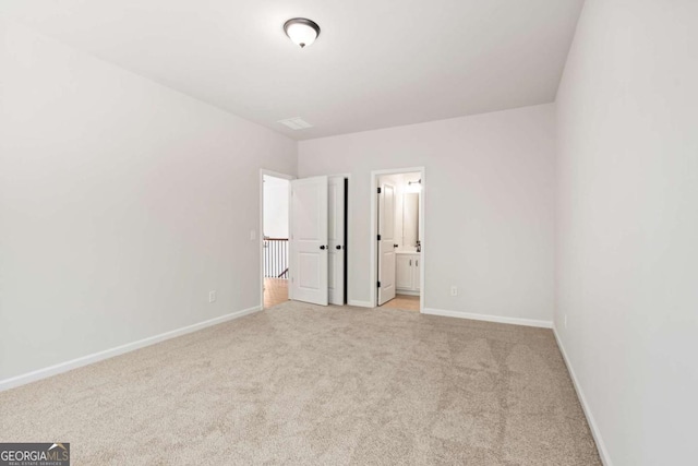 unfurnished bedroom with light carpet, baseboards, and connected bathroom