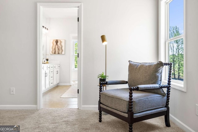 sitting room featuring healthy amount of natural light, light carpet, and baseboards
