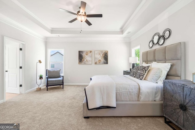 carpeted bedroom with a tray ceiling, crown molding, baseboards, and a ceiling fan