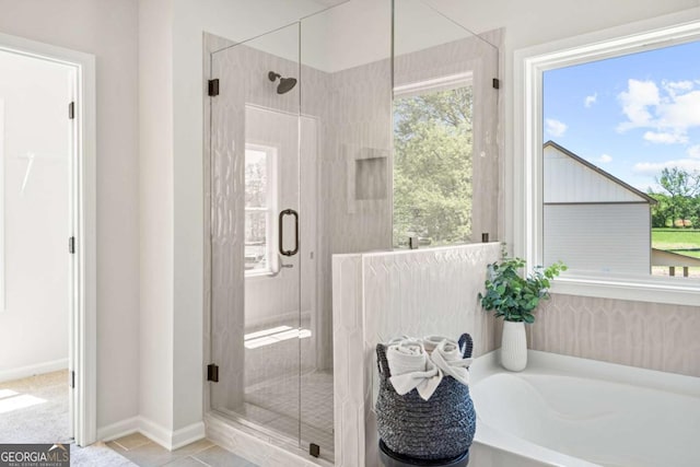 full bathroom with a stall shower, a bath, tile patterned floors, and baseboards
