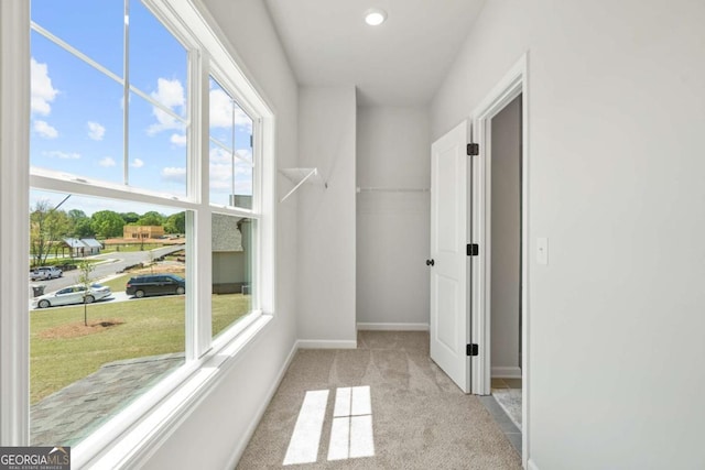 hallway with light carpet, healthy amount of natural light, baseboards, and recessed lighting