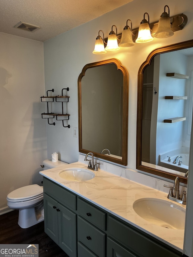 120 Magnolia Trl, Milner, GA 30257 - bathroom featuring toilet, double vanity, wood finished floors, a textured ceiling, and a tub to relax in