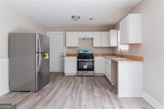 2172 Red Rose Ln, Loganville, GA 30052 - kitchen with stainless steel appliances, a sink, light wood finished floors, and white cabinetry
