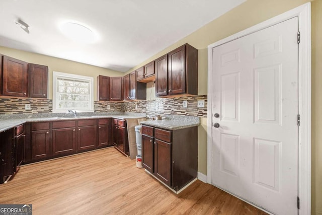 2703 Flagstone Dr SE, Atlanta, GA 30316 - kitchen with light wood finished floors, backsplash, light countertops, and dark brown cabinets