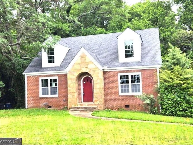 view of front of home with crawl space, brick siding, a front yard, and view of scattered trees