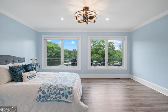 bedroom with multiple windows, a chandelier, wood finished floors, crown molding, and baseboards