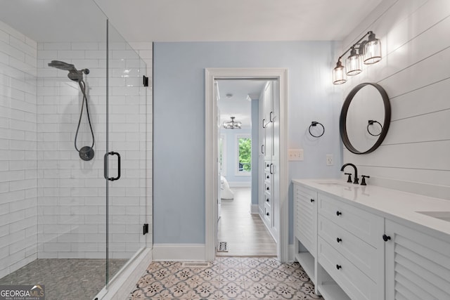 full bath with a shower stall, double vanity, and baseboards