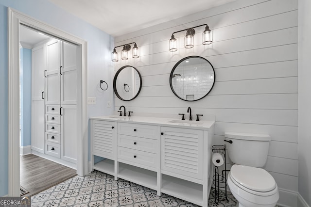 bathroom featuring toilet, double vanity, and baseboards