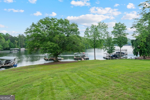 view of grassy yard featuring a water view and a dock
