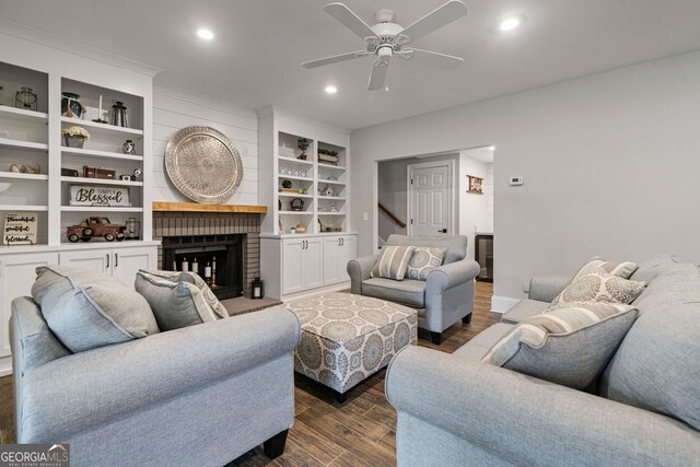 living area with dark wood-style flooring, a ceiling fan, a brick fireplace, recessed lighting, and stairway