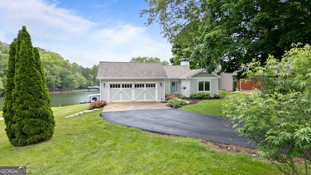 view of front of property featuring asphalt driveway, a chimney, a front yard, a water view, and a garage