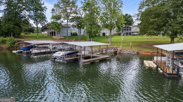 dock with a water view, boat lift, and a lawn