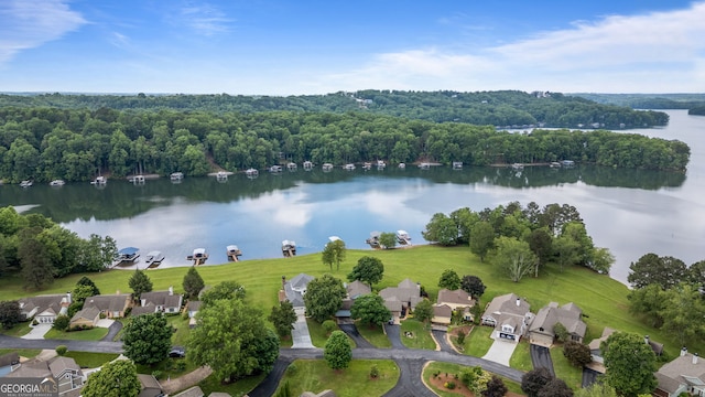 aerial view of property and surrounding area with a large body of water, nearby suburban area, and a heavily wooded area