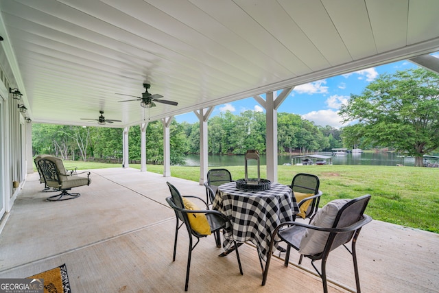 view of patio / terrace featuring a water view, ceiling fan, view of scattered trees, and outdoor dining area