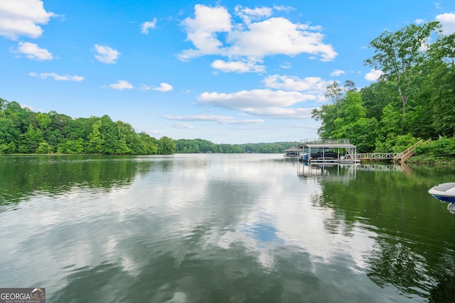 water view featuring a forest, a boat dock, and boat lift