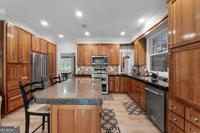 130 Allie Dr, Mcdonough, GA 30252 - kitchen featuring appliances with stainless steel finishes, a kitchen bar, light wood-style flooring, ornamental molding, and brown cabinets