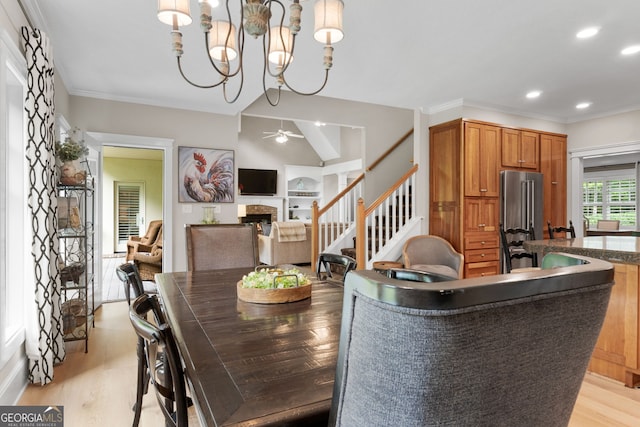 130 Allie Dr, Mcdonough, GA 30252 - dining room with a fireplace, stairs, light wood-type flooring, ceiling fan, and a chandelier