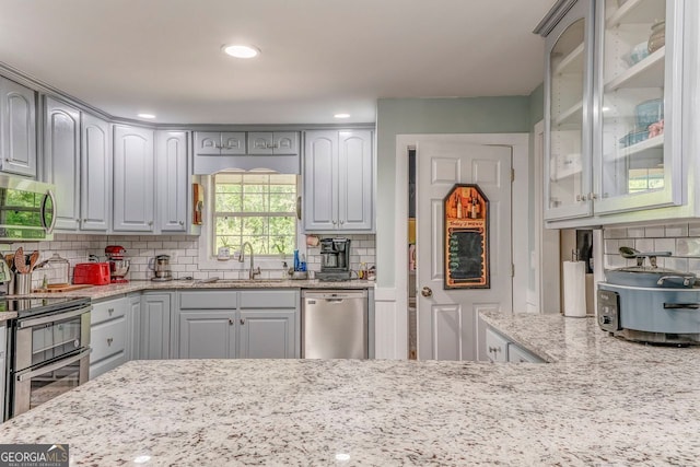 46 SW Colleen Karen Rd SW, Euharlee, GA 30120 - kitchen with stainless steel appliances, a sink, glass insert cabinets, light stone counters, and backsplash