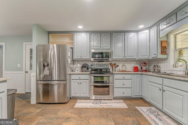 46 SW Colleen Karen Rd SW, Euharlee, GA 30120 - kitchen featuring stainless steel appliances, a sink, light stone finish flooring, backsplash, and wainscoting