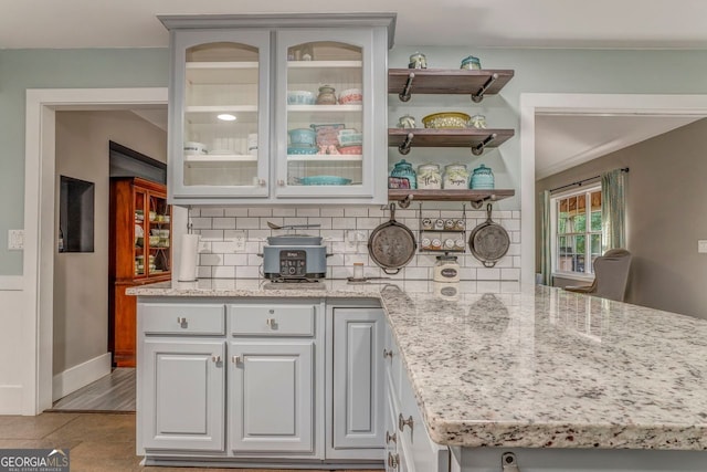 46 SW Colleen Karen Rd SW, Euharlee, GA 30120 - kitchen with backsplash, glass insert cabinets, light stone countertops, and a peninsula