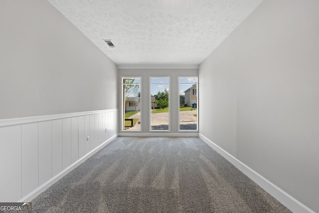 1404 Meadowind Ct SW, Conyers, GA 30094 - spare room with a textured ceiling, carpet, baseboards, and a wainscoted wall