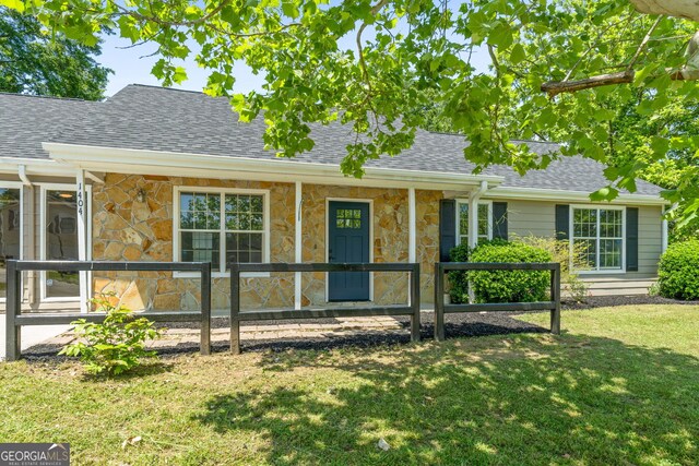 1404 Meadowind Ct SW, Conyers, GA 30094 - view of front of property with stone siding, a shingled roof, a front yard, and a porch