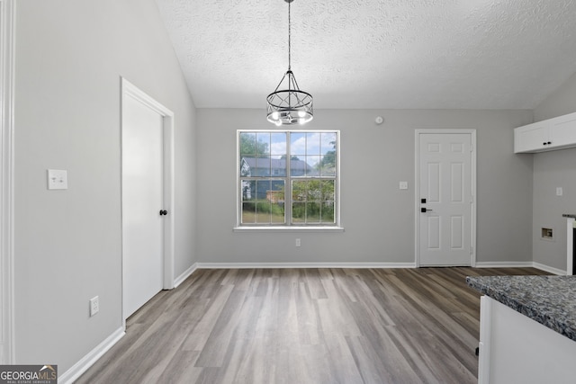 1404 Meadowind Ct SW, Conyers, GA 30094 - unfurnished dining area with wood finished floors, a textured ceiling, a chandelier, and baseboards