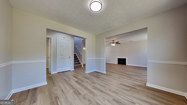 10961 Big Sky Dr, Hampton, GA 30228 - unfurnished room featuring a textured ceiling, light wood-style flooring, a fireplace, stairway, and ceiling fan