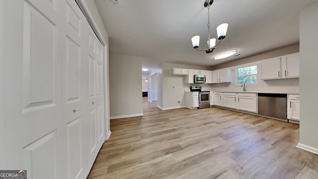 10961 Big Sky Dr, Hampton, GA 30228 - kitchen featuring stainless steel appliances, white cabinets, light wood-style floors, and pendant lighting