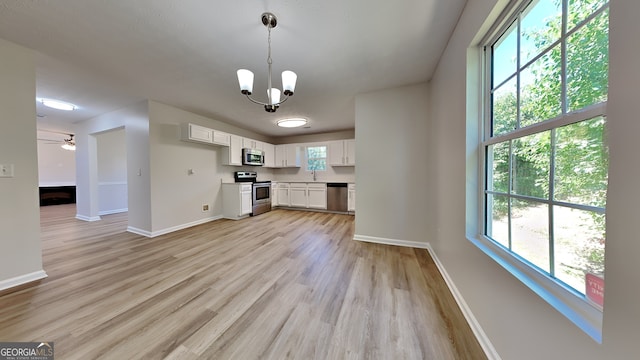 10961 Big Sky Dr, Hampton, GA 30228 - kitchen featuring stainless steel appliances, light wood finished floors, white cabinets, a chandelier, and pendant lighting
