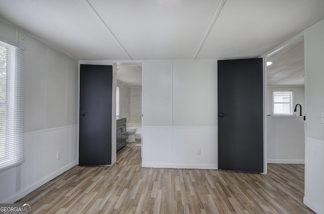 unfurnished room with light wood-type flooring, a decorative wall, and a wainscoted wall