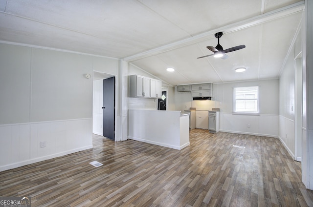 unfurnished living room with wood finished floors, ceiling fan, a wainscoted wall, a decorative wall, and crown molding