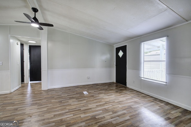 foyer featuring wood finished floors, vaulted ceiling, a ceiling fan, a decorative wall, and crown molding