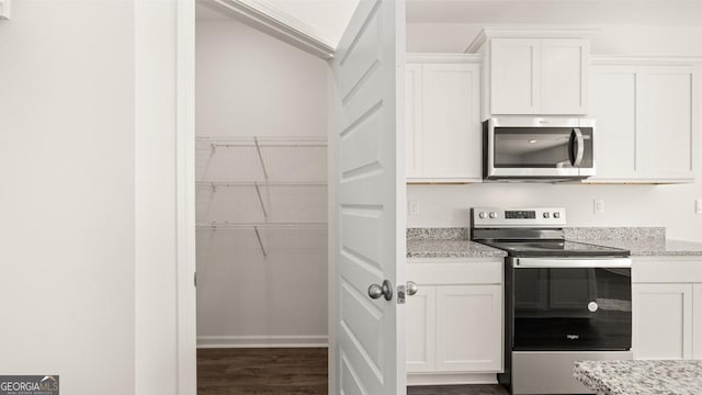 75 Poplar Blvd, Newnan, GA 30265 - kitchen featuring appliances with stainless steel finishes, white cabinetry, dark wood-type flooring, and light stone counters